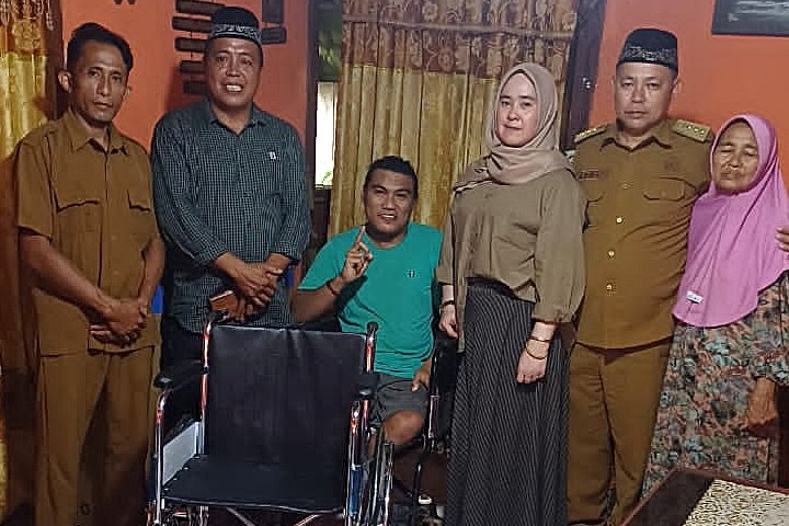 Bupati Boltim Oskar Manoppo menyerahkan kursi roda di Desa Loyow kepada warga disabilitas.